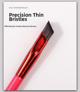 Detail of angled bristles on wild eyebrow brush with pink handle and red metal ferrule