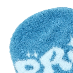 Close-up of soft blue plush faux fur knit beanie fabric with detailed letter embroidery