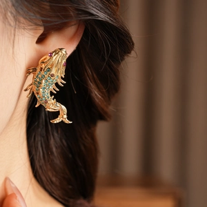 Close-up of a vintage koi fish earring with blue and purple crystals on a model's ear