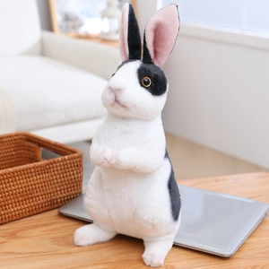 Detailed view of realistic black and white plush rabbit sitting on a wooden desk