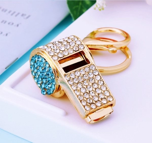 Macro shot of gold-plated whistle keychain with sparkling blue and clear rhinestones