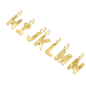 Macro shot of gold-plated stainless steel letter charms H to N with sunburst texture