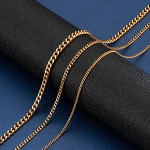 Three gold stainless steel chains with curb and box links on a black stand