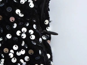 Close-up of sparkling silver sequins on black plush fabric with an invisible zipper detail