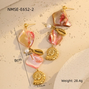 Detail of seashell earrings with pink shells, pearls and gold starfish pendants on stone