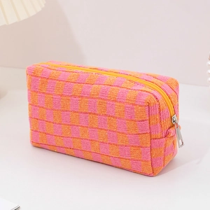 Detail of pink and orange checkered knit makeup bag with yellow zipper and silver puller