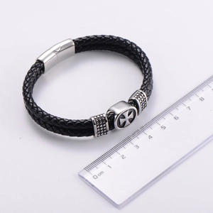 Dettaglio del bracciale da uomo in pelle intrecciata a doppio strato con croce