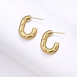 Detail of chunky gold hoop earrings with embossed stars and a polished metallic finish