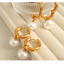 Macro shot of elegant gold-plated hoop earrings with natural white pearl pendants