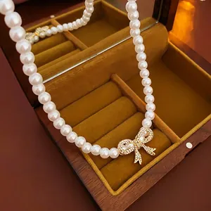 Faux pearl necklace with a sparkling diamond-encrusted bow pendant in a jewelry box