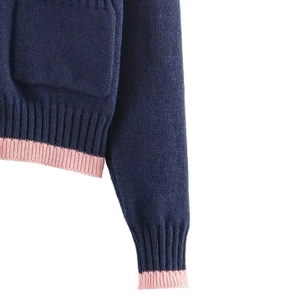 Détail du tissu en maille bleu foncé avec poignets côtelés roses et coutures de poche