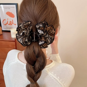 Detail of a large leopard print hair claw clip featuring double-layered pleated fabric textures