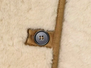 Detailansicht der Lammfelljacke mit cremefarbenem Fleece und braunem Knopf-Detail