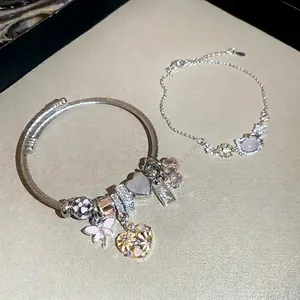 Silver charm bracelet set with enamel flower and diamond heart pendants on leather background