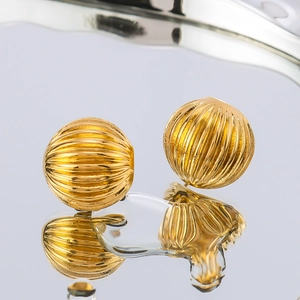 Textured gold hemispherical dome earrings for women on a reflective surface with water drops