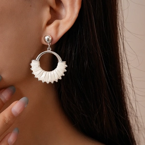 Close-up of model wearing silver round geometric earrings with white leather wrap detail