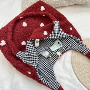 Detailed view of red fuzzy tote bag with white heart embroidery and checkered lining