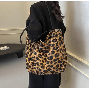 Detailed view of large leopard print quilted tote bag worn with a black wool coat