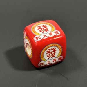 Macro shot of a red mahjong dice keychain with lucky Chinese character engraving