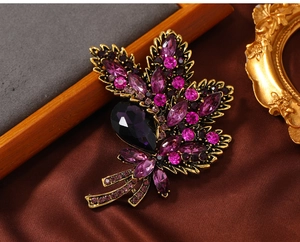 Macro shot of vintage gold flower brooch with purple rhinestones on brown velvet background
