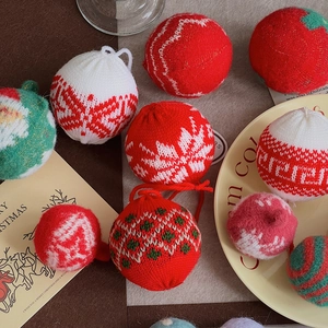 Flat lay of red, white, and green knitted Christmas tree ornaments with textured patterns