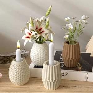 Détail de vases en céramique texturés et bougeoirs géométriques sur une table en bois
