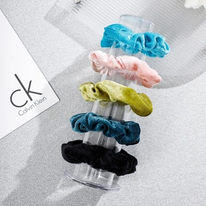 Cinq chouchous en velours de couleurs assorties sur un support vertical en acrylique