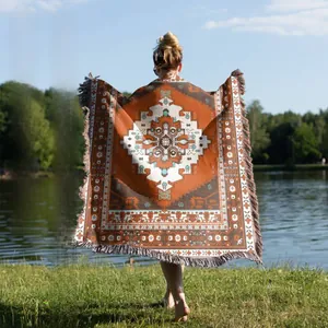 Close-up of bohemian woven picnic blanket with orange geometric patterns and gray tassels