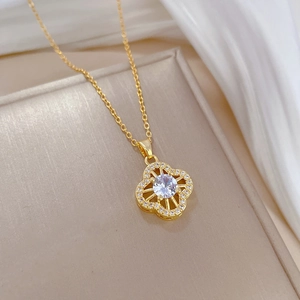 Macro view of gold clover necklace pendant with central zircon and pavé crystals
