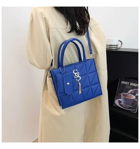 Borsa a tracolla blu in pelle con trapuntatura, hardware dorato e nappa indossata dal modello