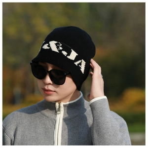 Close-up of black knit beanie with white jacquard lettering on outdoors lifestyle model