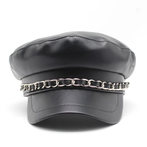 Detail of black leather newsboy cap showing metal chain strap and fine grain texture