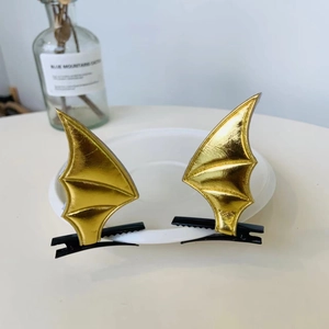 Detailed view of golden bat wing hair clips with faux leather texture for Halloween