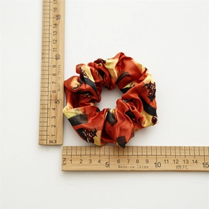 Halloween satin scrunchie with orange pumpkin patterns and witch hats on white background
