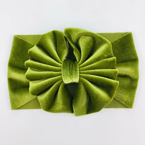 Detail of grass green velvet baby headband featuring a large multilayered ruffled flower
