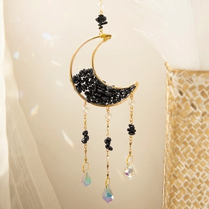 Detail of moon-shaped gold suncatcher with black crushed stones and crystal prisms