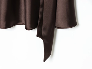 Détail de la robe en satin marron chocolat avec couture d'ourlet et texture de ceinture