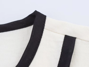 Detailed close-up showing precision stitching on cream and black contrast trim crepe top