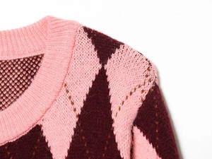 Detailed view of the pink and burgundy argyle knit texture and ribbed collar on the cardigan