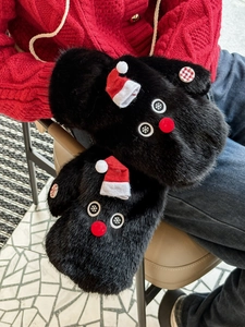 Close-up of black plush mittens with cute red hat snowman design for winter warmth