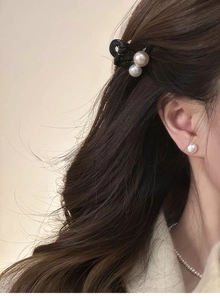 Détail de la pince à cheveux à double perle noire avec boucles d'oreilles et collier
