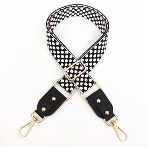 Adjustable black and white geometric woven bag strap with gold metal hooks and leather ends