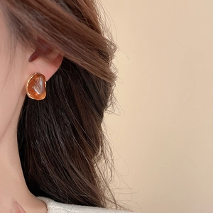 Gros plan de boucles d'oreilles vintage en résine avec bordure dorée sur un mannequin