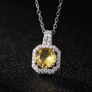 Macro shot of silver perfume bottle pendant with yellow zircon and pavé crystals on black
