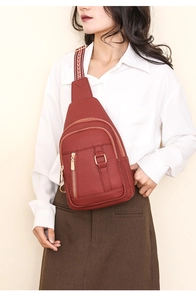 Detail of red PU leather chest bag with litchi texture and colorful woven shoulder strap