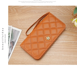 Detail of orange quilted wristlet wallet with golden camellia flower metal logo
