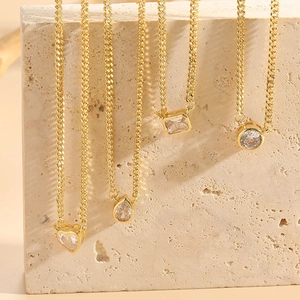 Detailed close-up of heart and teardrop zircon pendants on gold-tone chains