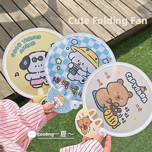 Detail of portable folding fans with cute cartoon dog and capybara graphics outdoors