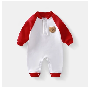 Detail eines Baby-Stramplers mit süßem Bären-Aufnäher und roten Rippbündchen am Ärmel