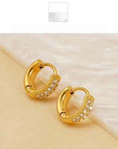 Close-up of gold titanium steel hoop earrings with three rows of sparkling zircon stones